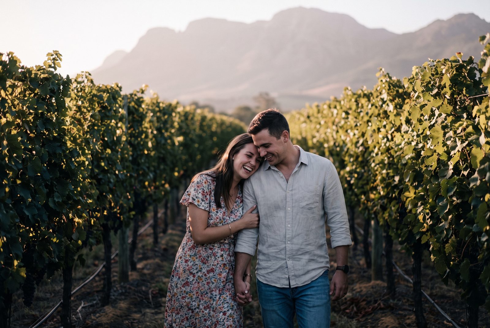 A young couple laughing together between the vines of a Stellenbosch vineyard